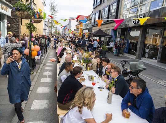 Fólk situr við langborð í göngugötunni Laugavegi.