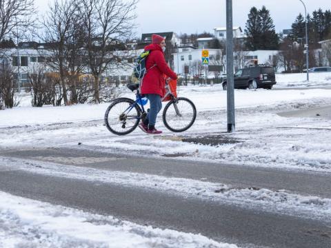 Kona á reiðhjóli á gatnamótum.