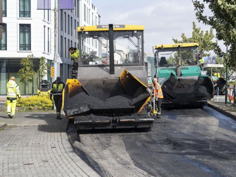 Stórar vélar og fólk við vinnu að malbika í Lækjargötu.