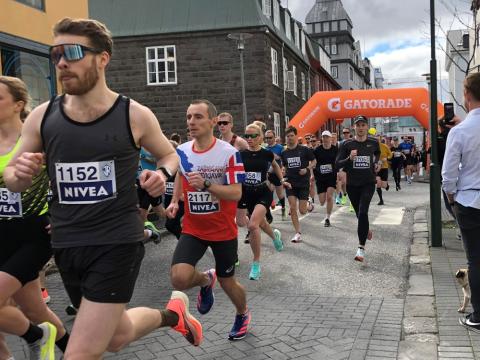 Hlauparar í víðavangshlaupi ÍR hlaupa um miðborgina. Appelsínugult Gatorade auglýsingaskilti yfir þeim.