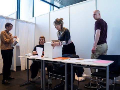 Four people staff a polling station in City Hall.