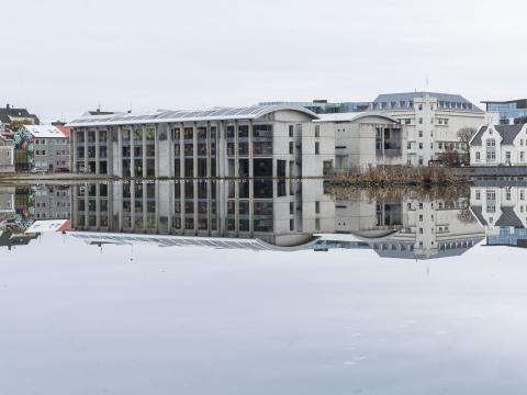 Ráðhús Reykjavíkur speglast í sléttri Tjörninni