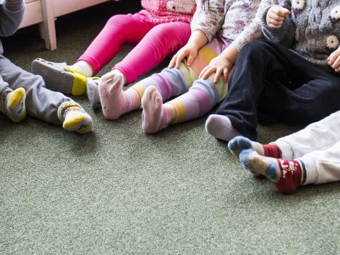 Feet of four children sitting in a circle at a preschool