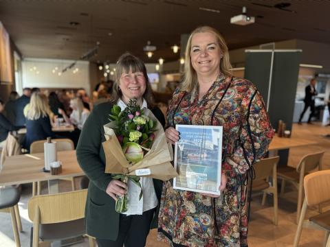 Tvær konur með blóm og viðurkenningu.