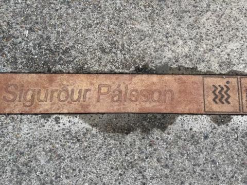 Bronze-colored sign in sidewalk with the name of author Sigurður Pálsson. Part of the literary installation at the Customs House.