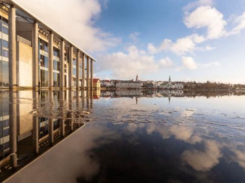 Hluti af Ráðhúsi Reykjavíkur speglast í Tjörninni í fallegu veðri