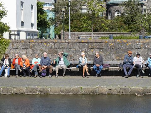 A group of older adults sits by Tjörnin pond in Reykjavík