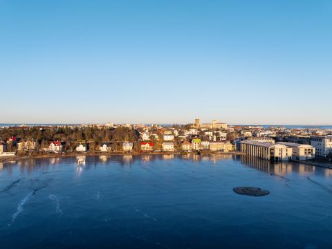 Tjörnin, Tjarnargatan, séð frá Þingholtum, loftmynd. Blá Tjörn í forgrunni, blár himinn í bakgrunni. Logn, heiður himinn.