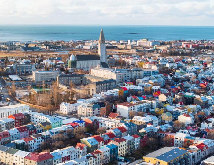 Loftmynd yfir miðborgina, Hallgrímskirkja fyrir miðju, fllugvöllur og sjór í baksýn. Sól.