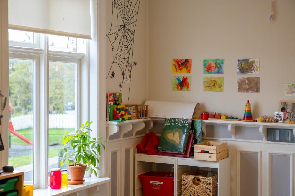 Myndir á vegg, leikföng og pottaplanta á leikskólanum Tjörn 