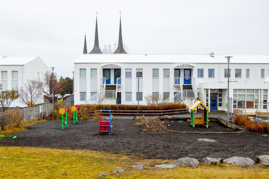 Leiktæki á útisvæði leikskólans Klambra. Hvítt hús leikskólans í baksýn ásamt turnum Háteigskirkju.