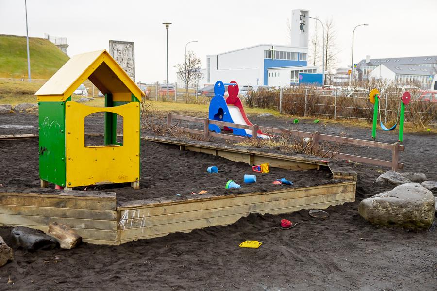 Sandkassi, lítið hús og rennibraut á útisvæði leikskólans Klambra