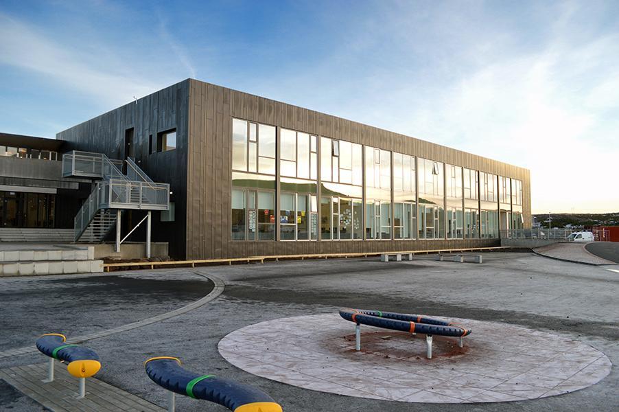 Picture of a large gray building with a window side where the youth center Plútó is located