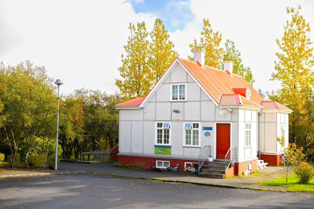 Leikskólinn Steinahlíð með há lauftré í baksýn