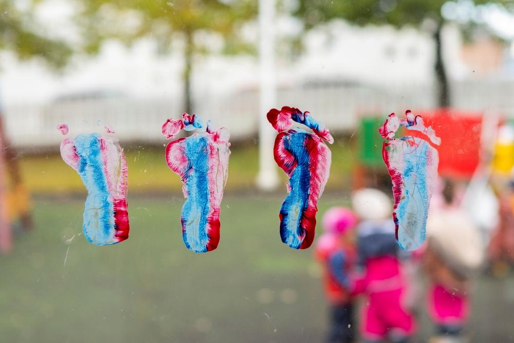 Small multicolored, stamped footprints on window at Miðborg Preschool, Barónsstígur