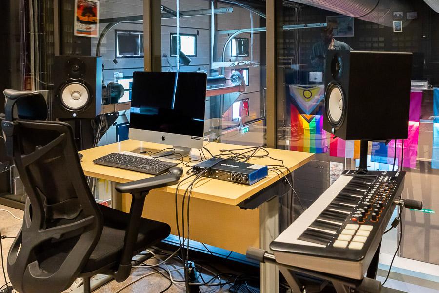 A computer desk, an office chair, speakers, and an electric piano.