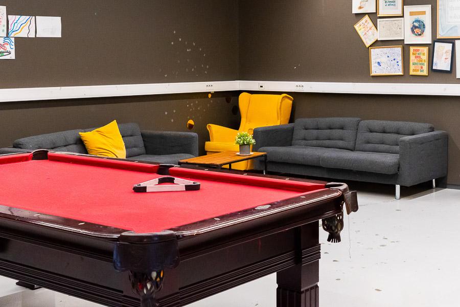 A pool table, gray couches, a coffee table, and a yellow chair. 