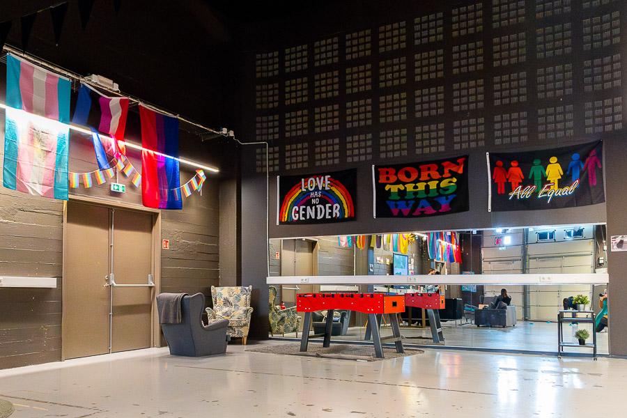 A hall with a foosball table, comfortable chairs, and equality flags. 