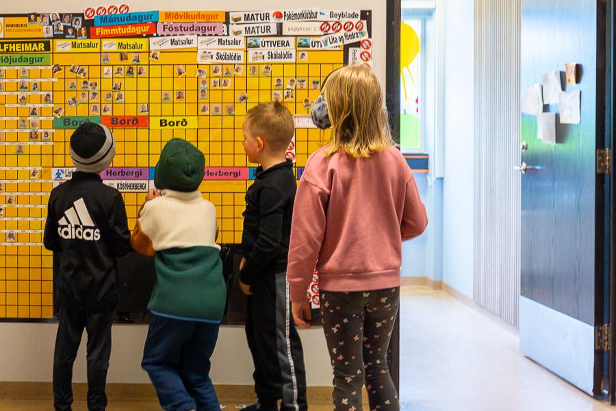 Börn að skoða skipulagstöflu Álfheima frístundaheimilis.
