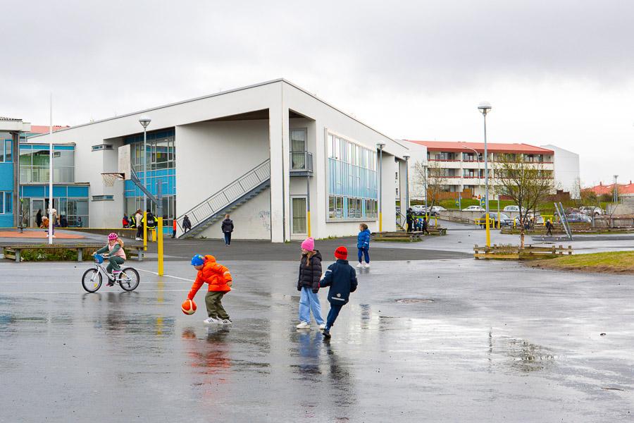 Börn að leik á útisvæði Hólabrekkuskóla. Skólinn í baksýn. 