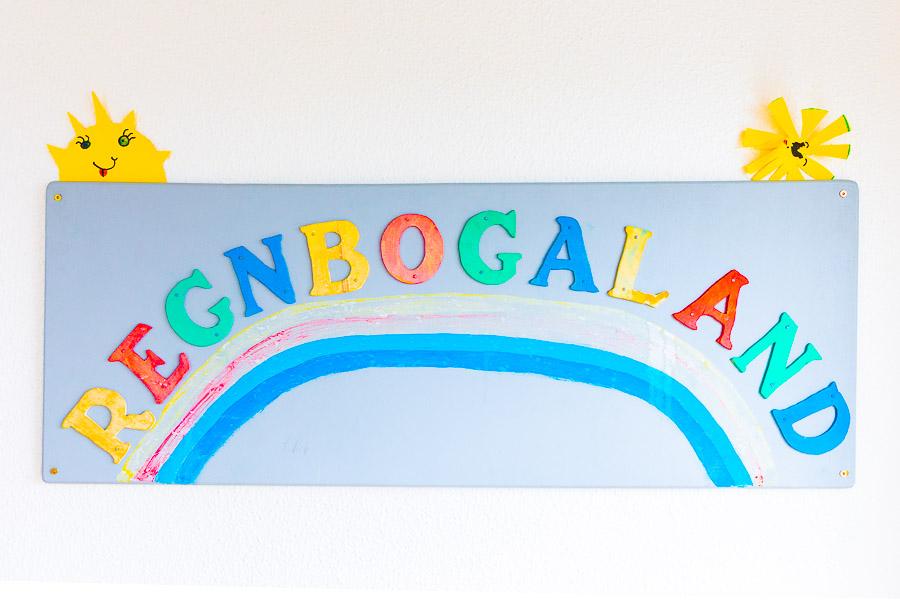 Skilti sem á stendur Regnbogaland  ásamt mynd af regnboga. 