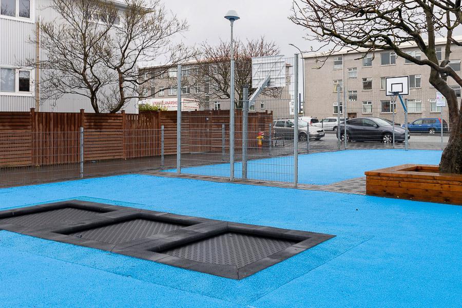 Útisvæði við Vesturbæjarskóla og Skýjaborgir frístundaheimili með bláu undirlagi og trampolíni.