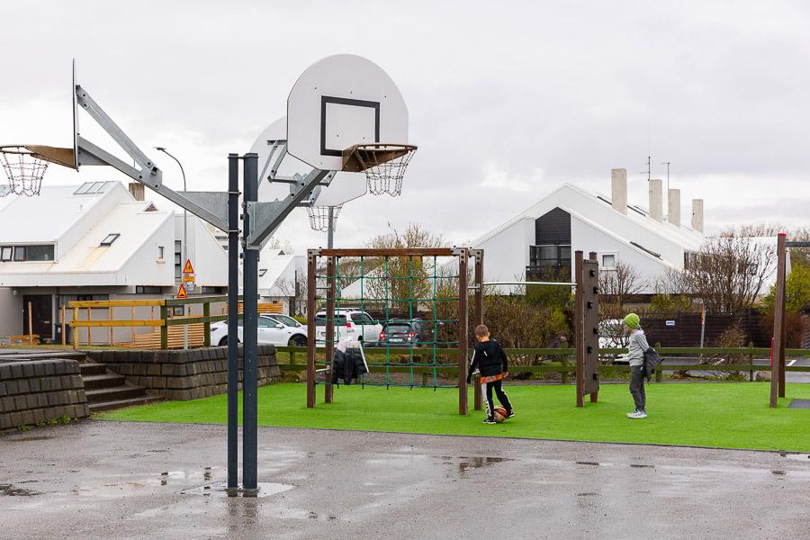 Körfuboltaspjald, klifurgrind og börn að spila fóltbolta. 