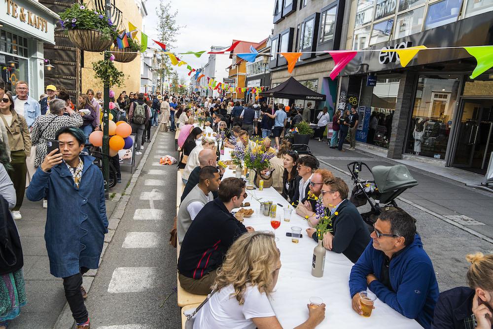 Fólk situr við langborð í göngugötunni Laugavegi.