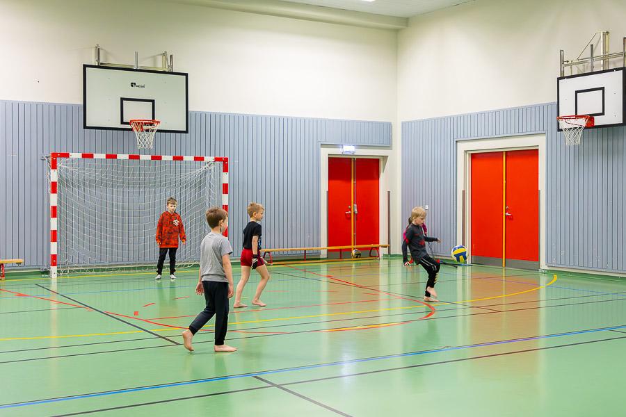 Börn að spila fótbolta á innivelli.
