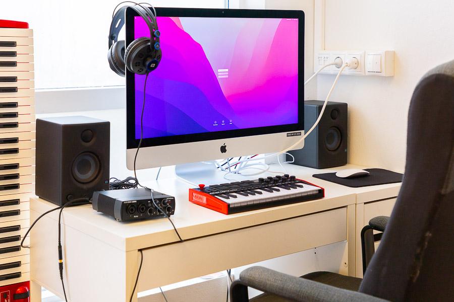 Table with a screen, electric keyboard, speakers and other equipment. 