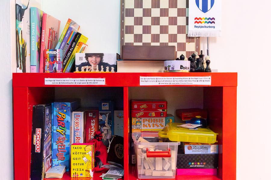 Red shelf with various games and chess sets.