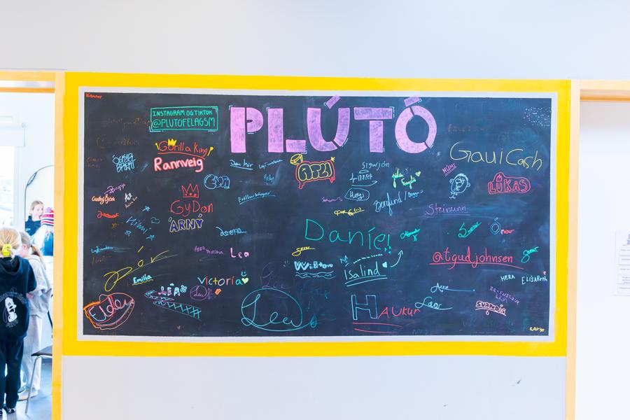 Chalkboard with the heading Plútó and signatures from many young people. 