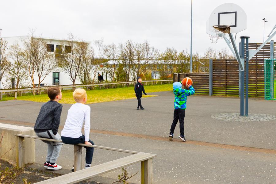 Börn á leikvelli á spila körfubolta.