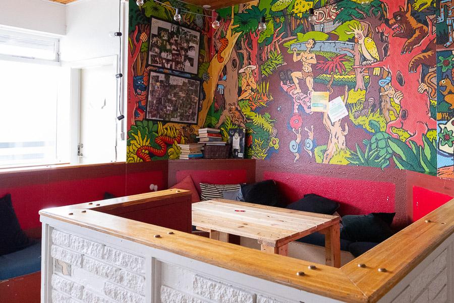 A corner decorated in red tones with cushions and a table. 