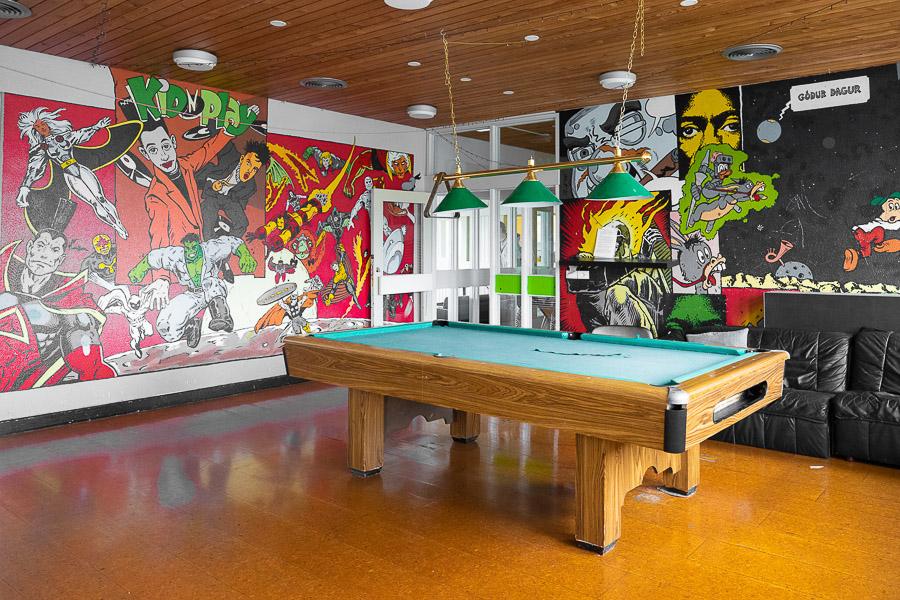 A room richly decorated with various figures on the walls and a pool table.