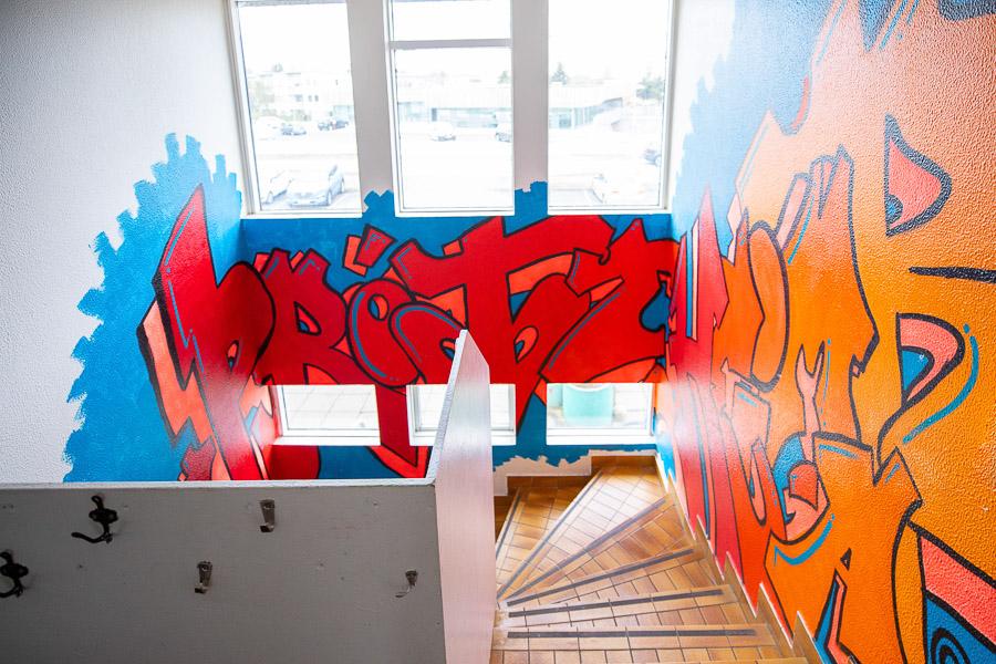 A stairway decorated with red and orange letters spelling out Þróttheimar.