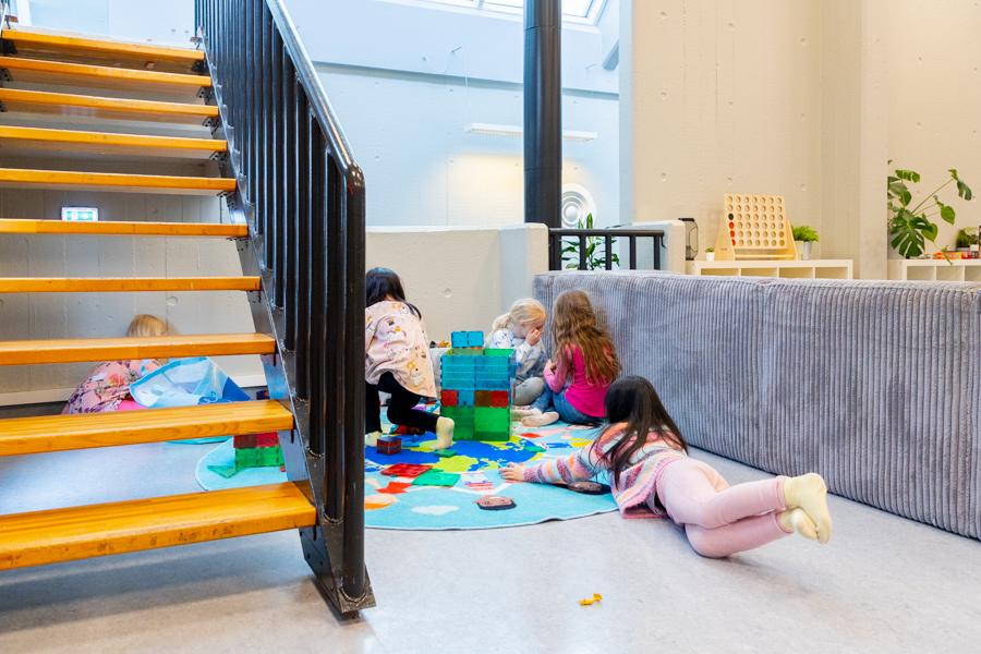 Hópur að börnum að leika sér á gólfinu með glæra kubba. Stigi til hliðar. 