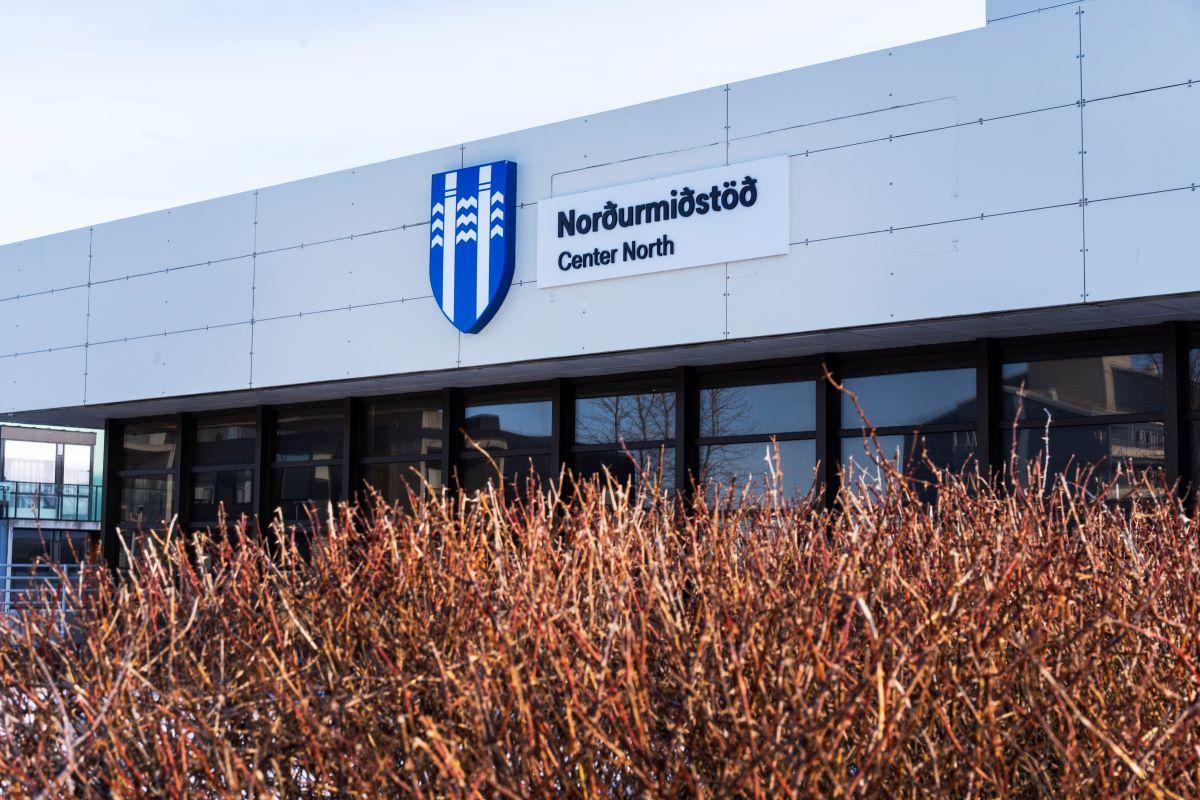 Hvítt hús með brúnum gluggum og runnar i haustlitum í forgrunni. Á húsinu er merki Reykjavíkurborgar og til hliðar stendur Norðurmiðstöð.