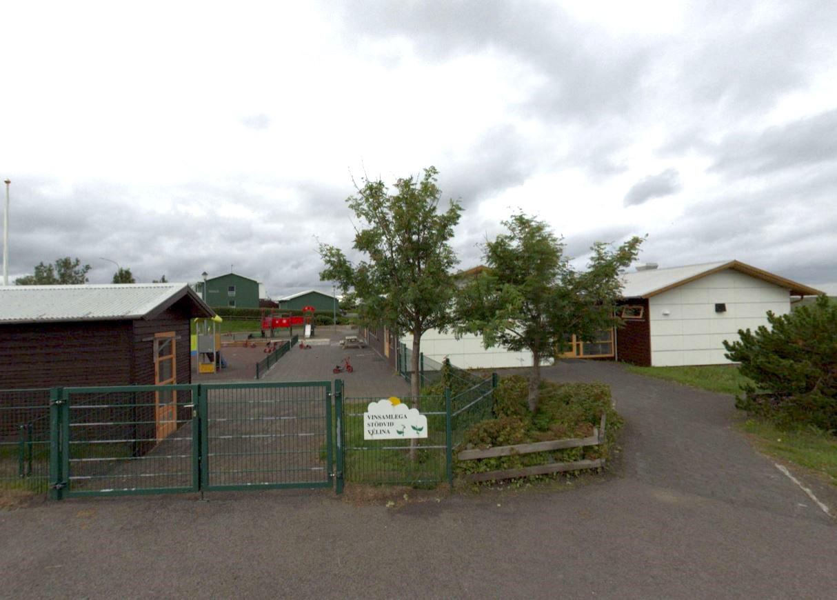 Bakkakot Preschool. Green gate in the foreground with trees on the right. 