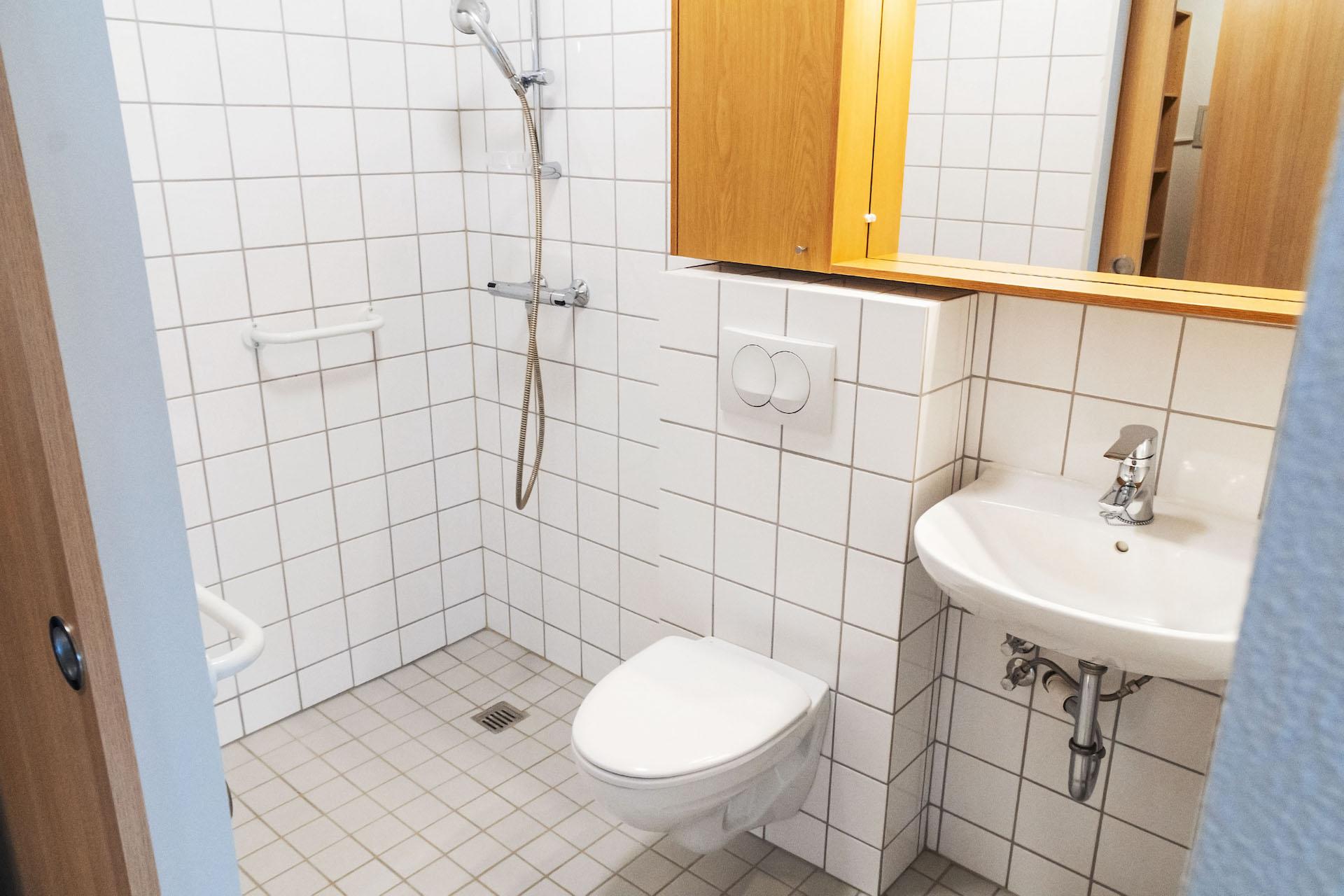 Lítið baðherbergi, flísalagt með litlum hvítum flísum