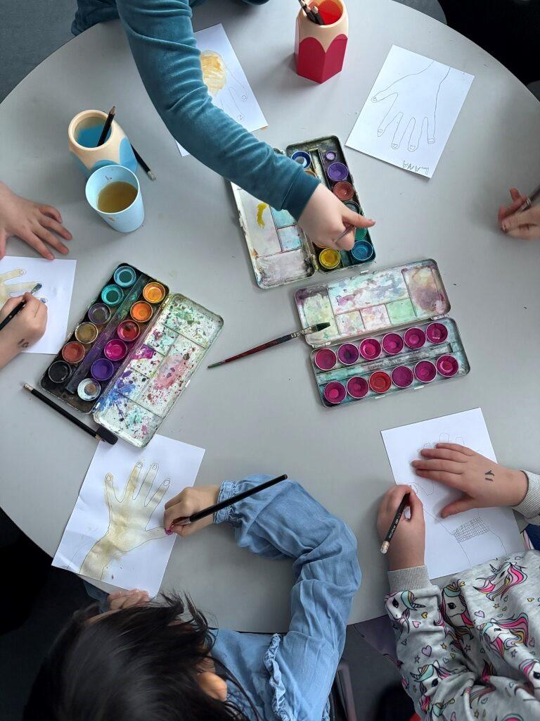 Children painting hands on paper.