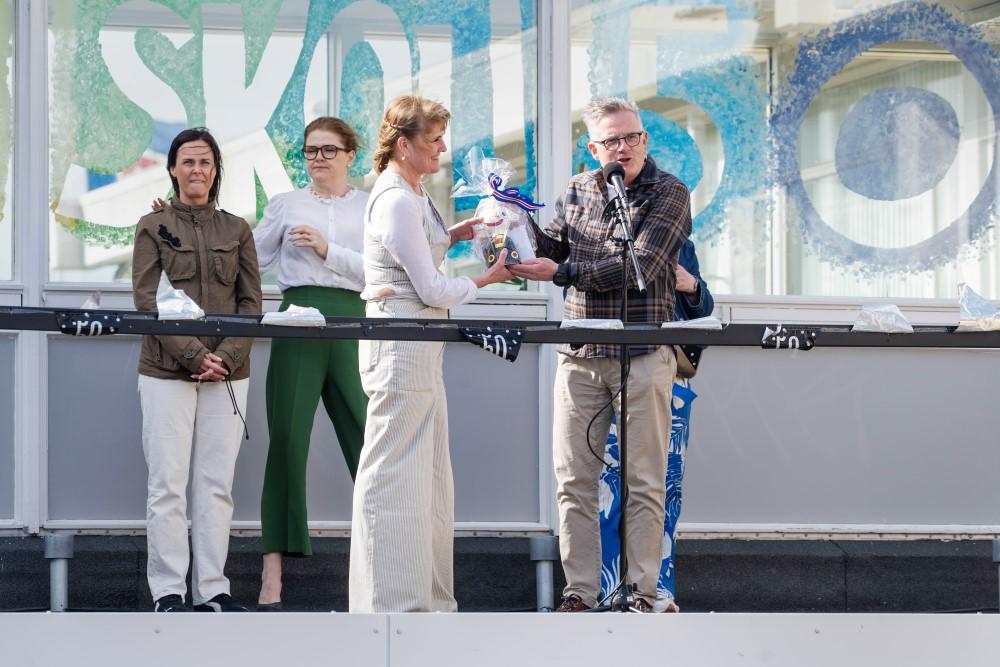 Helgi Gíslason, principal of Fellaskóli, presents flowers to Erla Erlendsdóttir, principal of Ölduselsskóli, in honor of the anniversary
