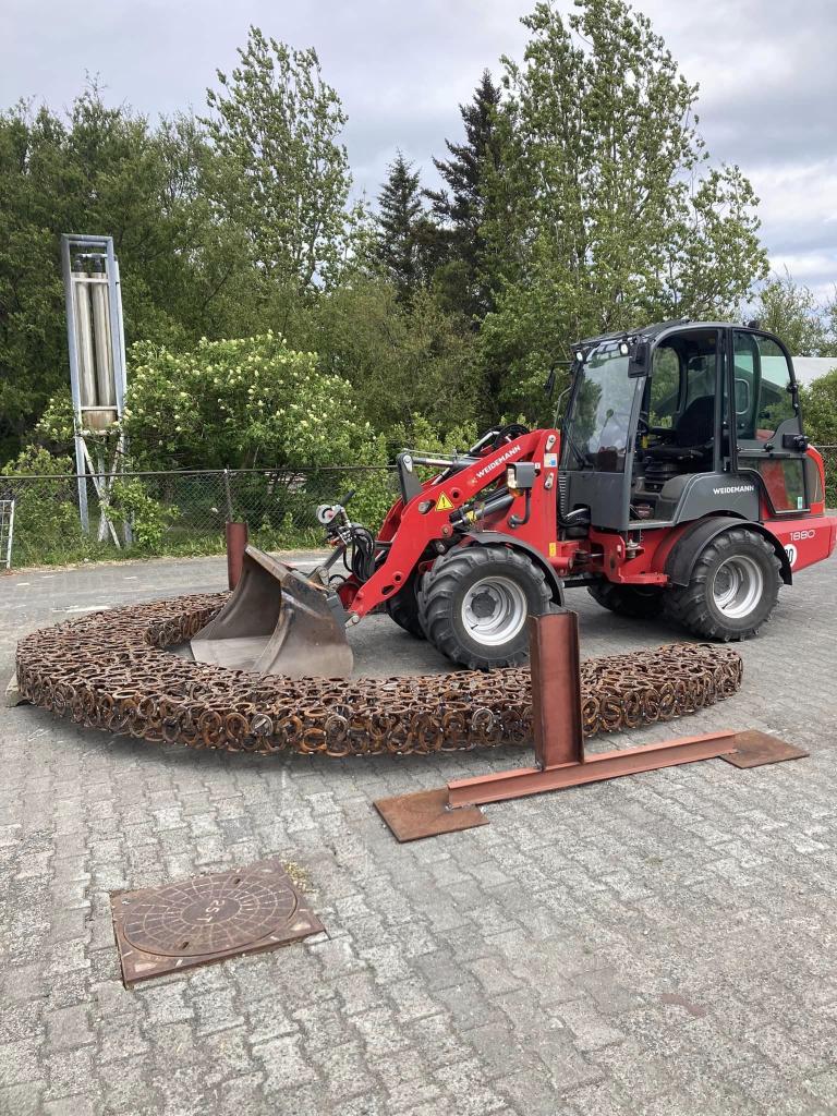 Grafa að vinna við að reisa upp listaverk úr skeifum.