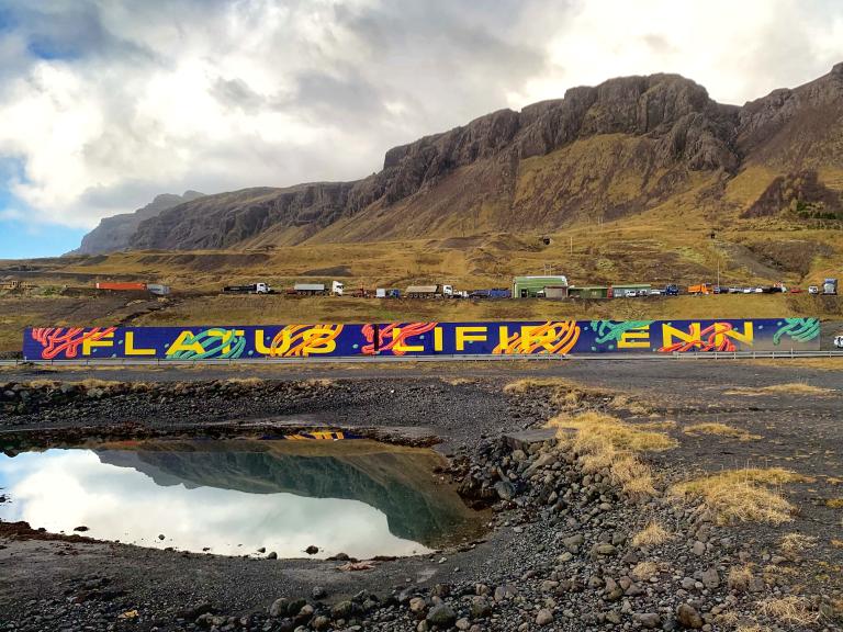 Vegglistaverkið Flatus lifir enn, við Esjurætur. Pollur í forgrunni, Esjan í bakgrunni.