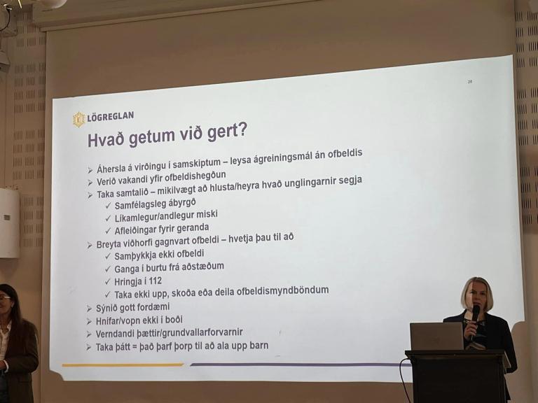 From a workshop at Valsheimili about children in vulnerable situations. Slide saying "What can we do?" and a woman at a podium discussing the slide's content