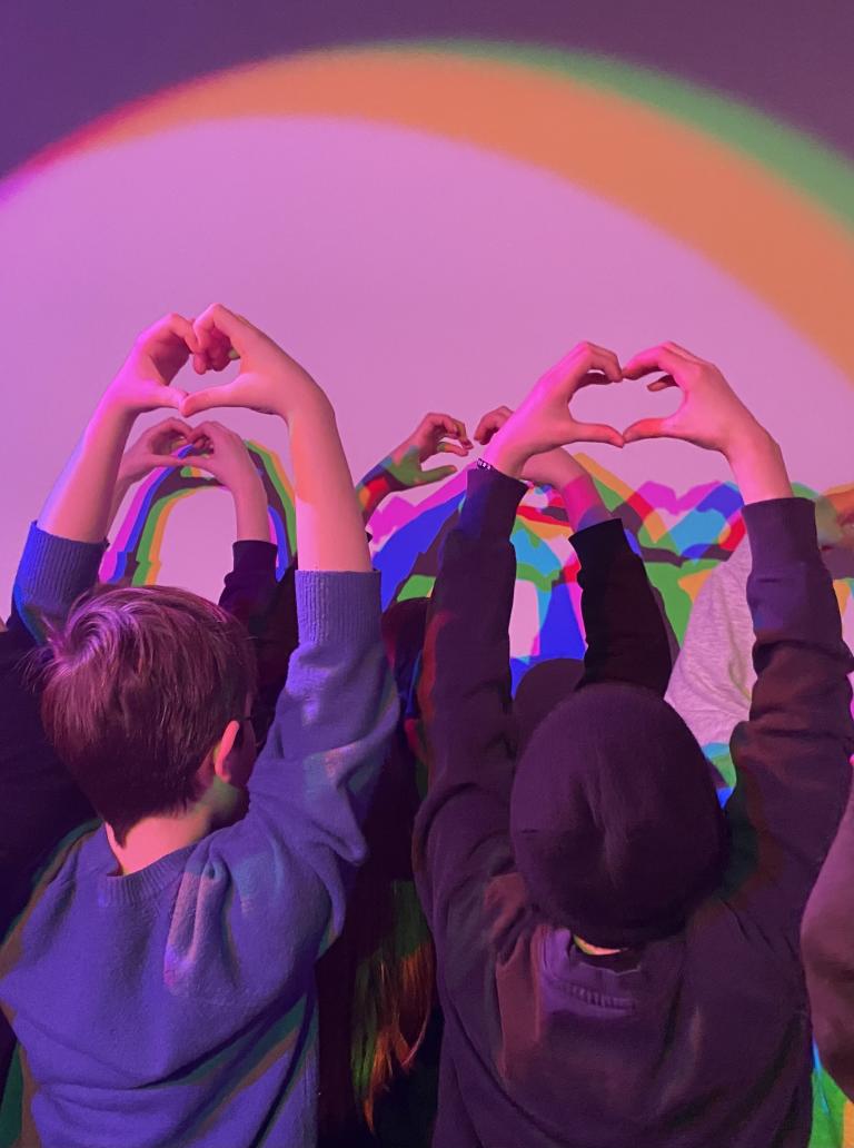Children express creativity by forming heart shapes with their fingers.