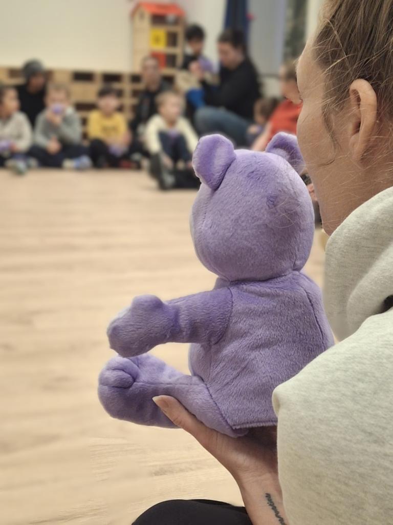 Photo of the large Blær plush toy sitting in a circle with the children.