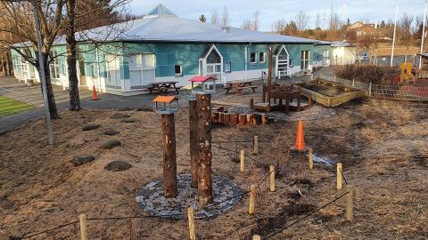 Leikskólinn Sólborg. Séð frá leiksvæði með fuglahúsum og leiktækjum