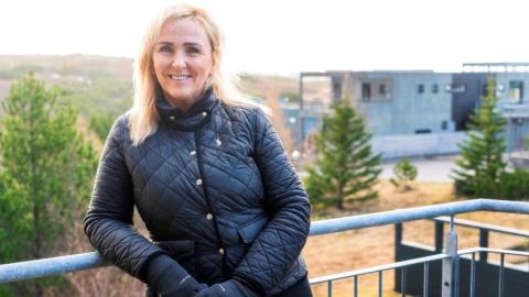 Heiða Björk Júlíusdóttir situr í íbúaráði Grafarholts og Úlfarsárdals. Hér er hún á svölunum sínum, í úlpu og hönskum, hallar sér upp að svaragrindverki með hverfið og náttúruna í bakgrunni.