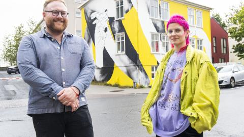 Adam Flint Taylor, program director of graphic design, and artist Natka Klimowicz stand in front of Andrými, featuring a mural.